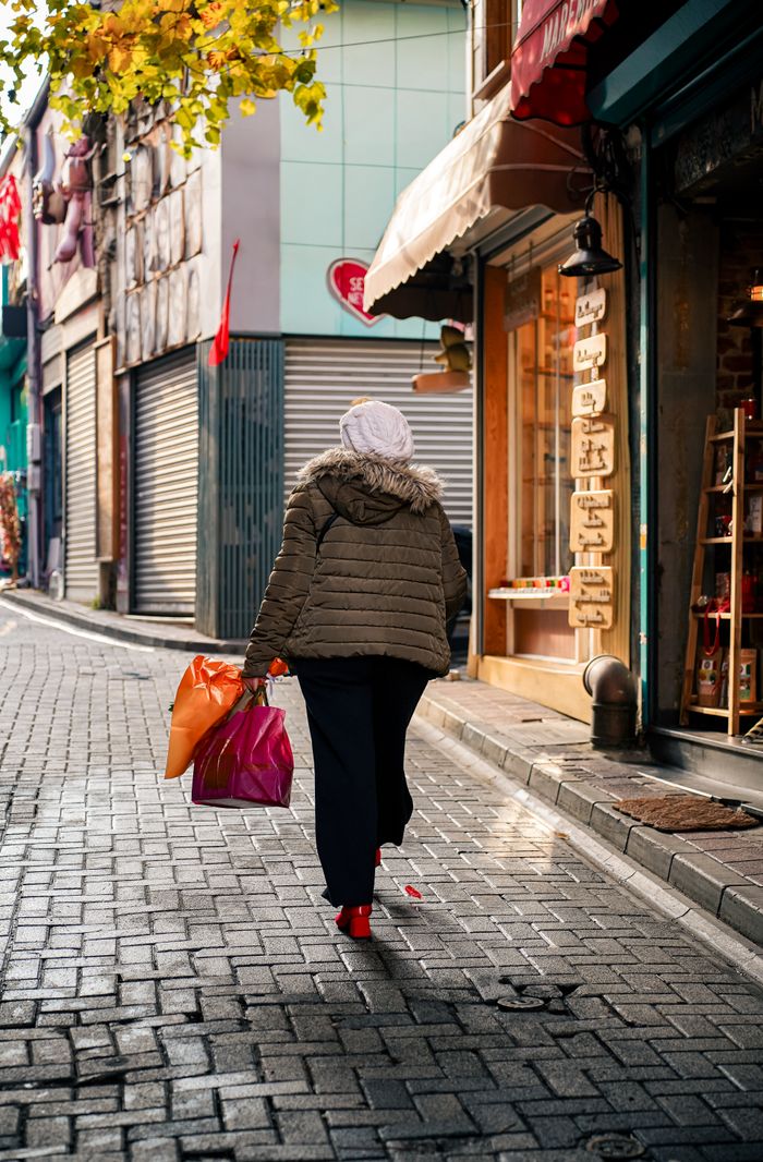 product-04 A woman shopping on a bustling urban street during the fall season.