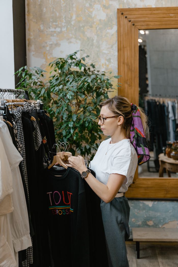 Home Fashion-conscious woman browsing a boutique clothing rack with elegant apparel indoors.