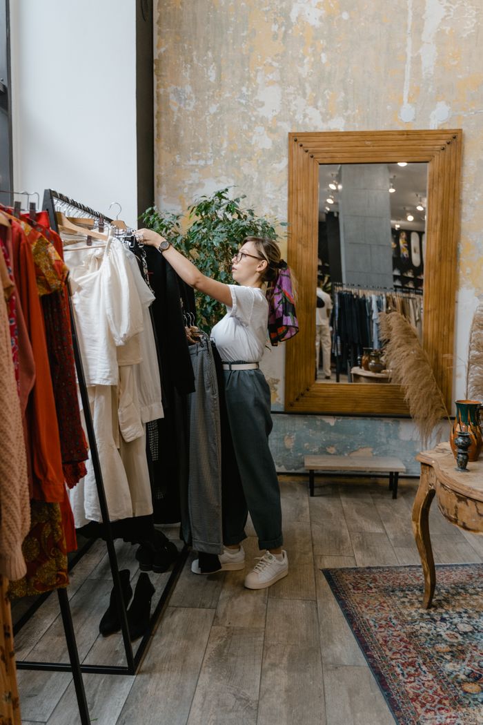 Home Woman browsing clothes rack in contemporary clothing store interior.